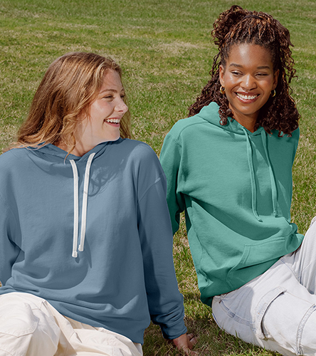 two ladies sitting on the grass wearing sweatshirts